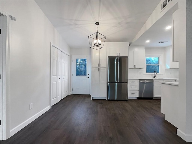 kitchen featuring tasteful backsplash, white cabinetry, hanging light fixtures, dark wood-type flooring, and stainless steel appliances