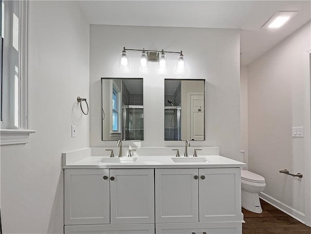 bathroom with hardwood / wood-style floors, toilet, walk in shower, and vanity