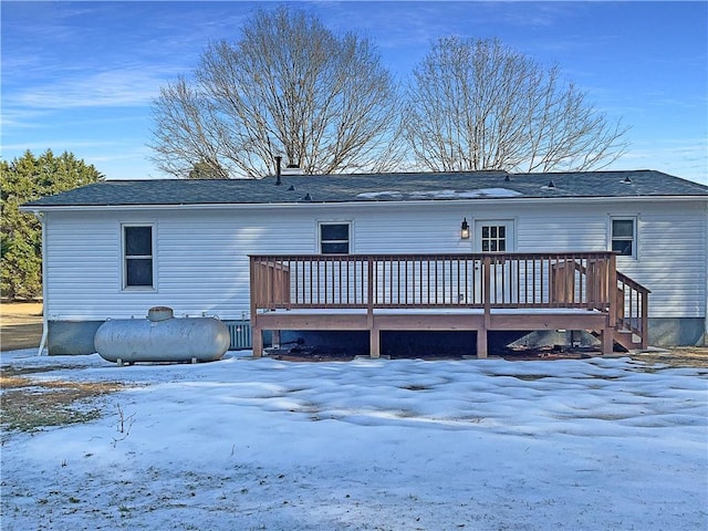 snow covered back of property with a wooden deck