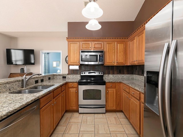 kitchen featuring light stone countertops, sink, stainless steel appliances, backsplash, and pendant lighting