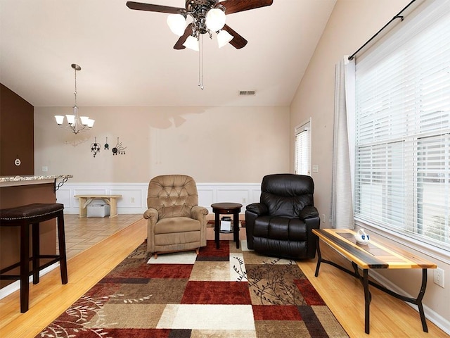 sitting room featuring plenty of natural light, ceiling fan with notable chandelier, vaulted ceiling, and hardwood / wood-style flooring