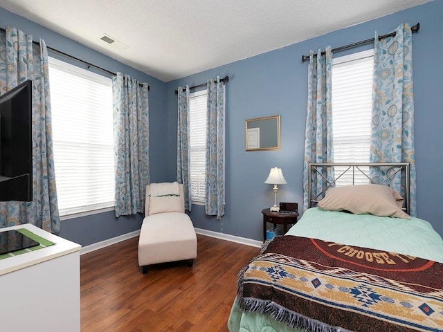 bedroom featuring a textured ceiling, multiple windows, and dark wood-type flooring