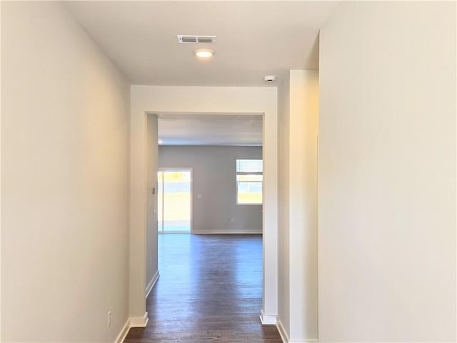 hall with visible vents, dark wood finished floors, and baseboards