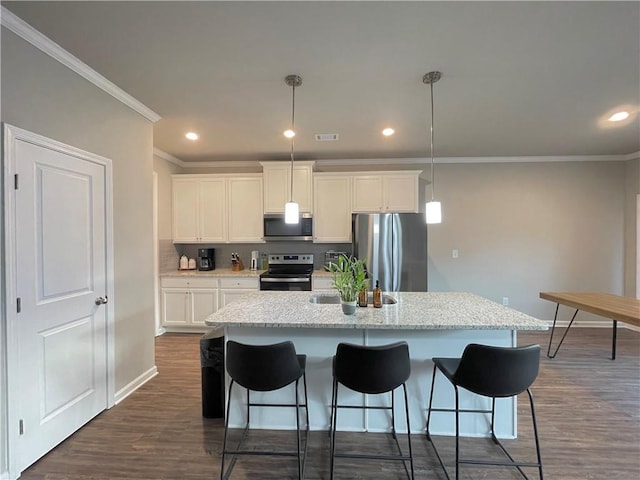 kitchen featuring decorative light fixtures, white cabinets, stainless steel appliances, and a kitchen island with sink