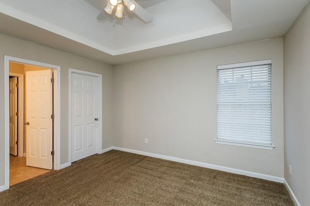 unfurnished bedroom with carpet floors, a raised ceiling, and ceiling fan