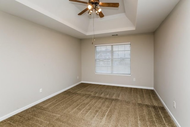 spare room featuring a tray ceiling, carpet floors, and ceiling fan