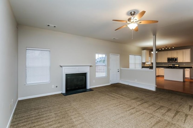 unfurnished living room with ceiling fan, track lighting, and dark colored carpet