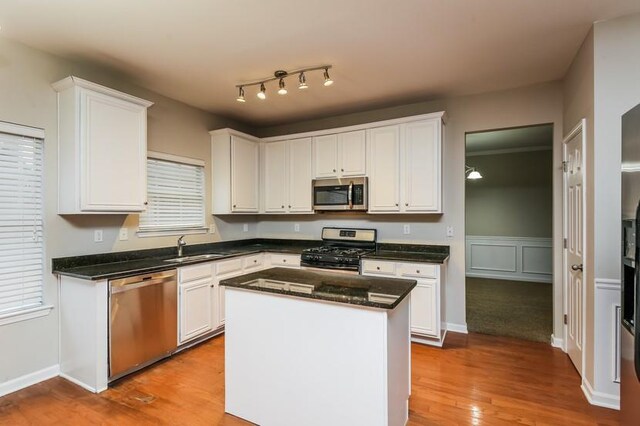 kitchen with sink, white cabinetry, stainless steel appliances, a center island, and light wood-type flooring