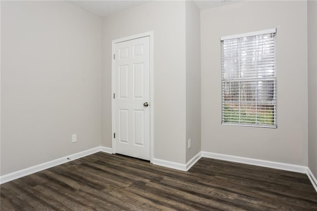 spare room featuring baseboards and dark wood-style floors