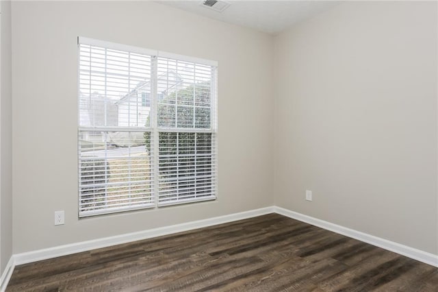 unfurnished room with baseboards, dark wood-type flooring, and visible vents