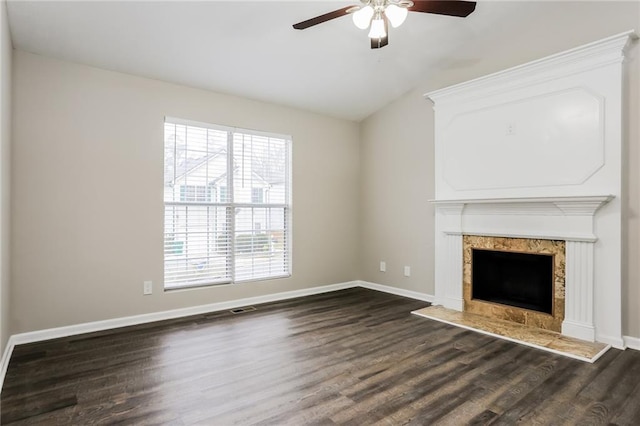 unfurnished living room featuring a premium fireplace, visible vents, dark wood-style flooring, ceiling fan, and vaulted ceiling