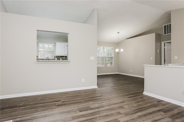 empty room featuring an inviting chandelier, dark wood finished floors, visible vents, baseboards, and vaulted ceiling