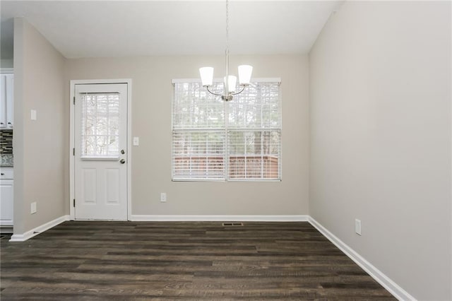 unfurnished dining area with a chandelier, baseboards, a healthy amount of sunlight, and dark wood finished floors