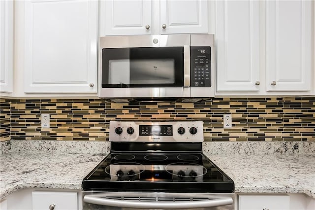 kitchen featuring light stone countertops, white cabinets, appliances with stainless steel finishes, and tasteful backsplash