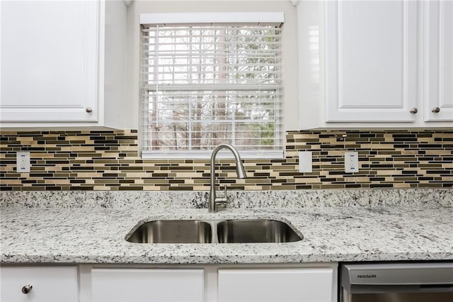 kitchen with white cabinetry, backsplash, a sink, and stainless steel dishwasher