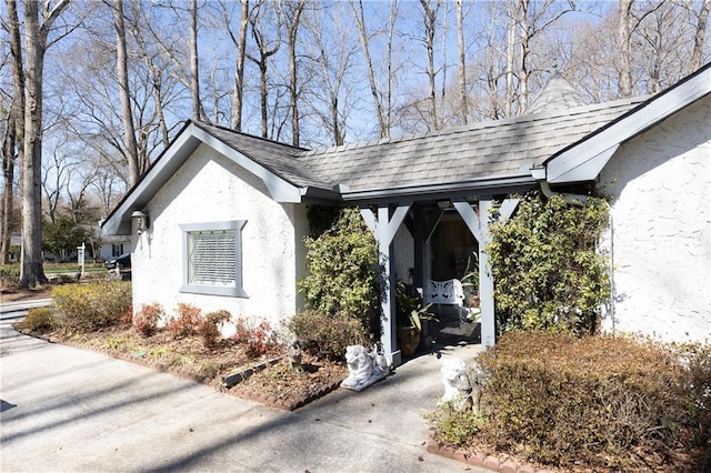 view of side of home featuring roof with shingles and stucco siding