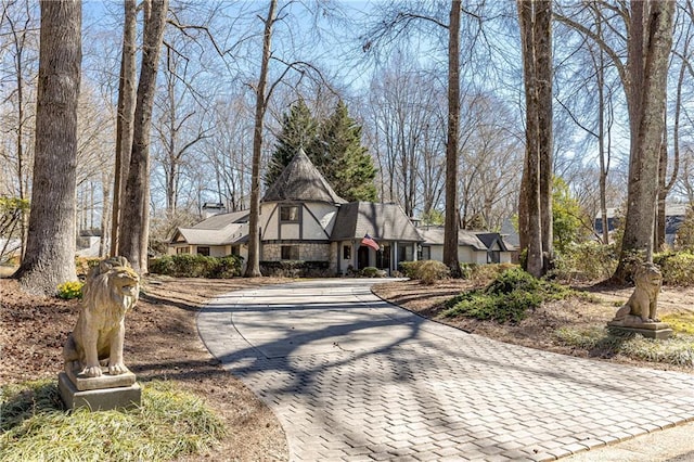 english style home featuring stone siding and decorative driveway