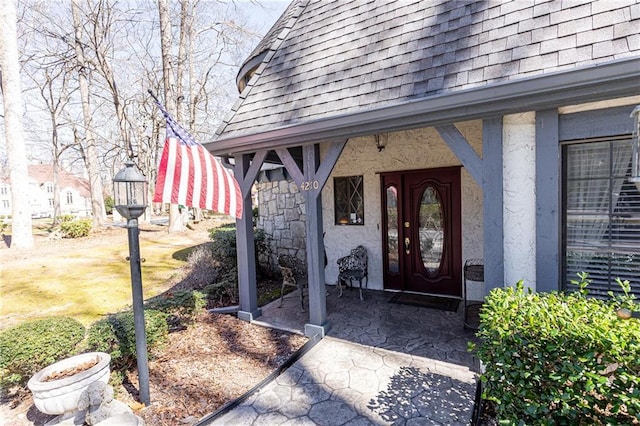 property entrance featuring roof with shingles and stucco siding