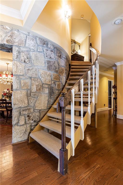 staircase featuring ornamental molding, baseboards, and wood finished floors