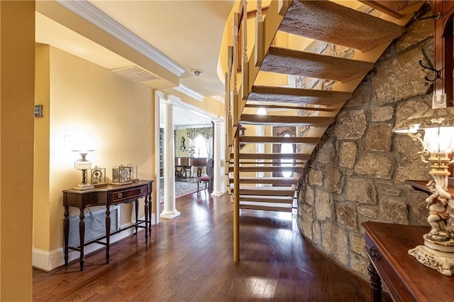 corridor with ornate columns, wood-type flooring, stairway, and crown molding