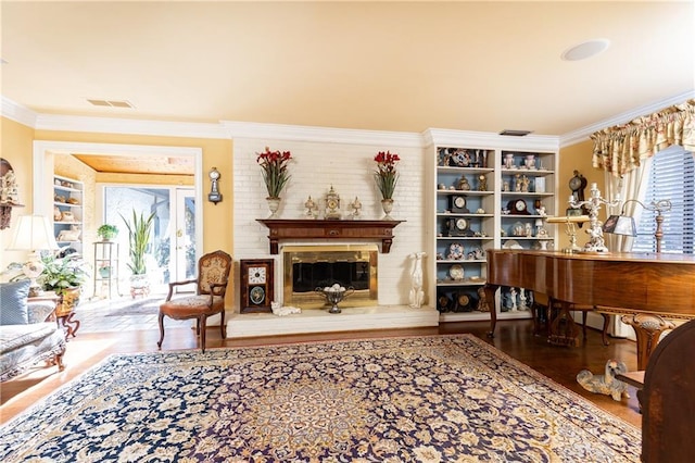 living area featuring visible vents, wood finished floors, crown molding, and a glass covered fireplace