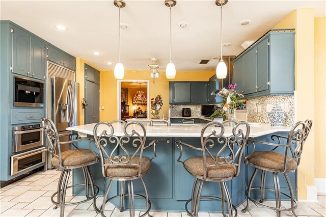 kitchen with a peninsula, tasteful backsplash, stainless steel appliances, and light countertops