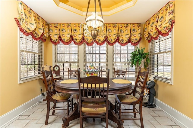 dining area with a chandelier, a tray ceiling, crown molding, and baseboards