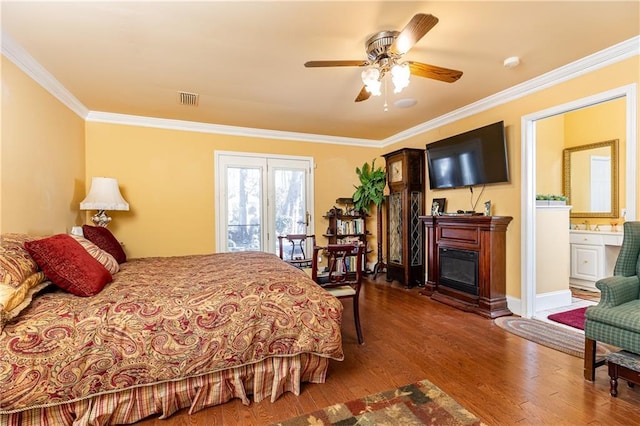 bedroom featuring visible vents, a glass covered fireplace, wood finished floors, access to exterior, and crown molding