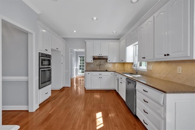 kitchen with white cabinetry, under cabinet range hood, appliances with stainless steel finishes, and a sink