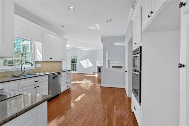 kitchen with dark stone countertops, white cabinetry, a sink, decorative backsplash, and stainless steel dishwasher