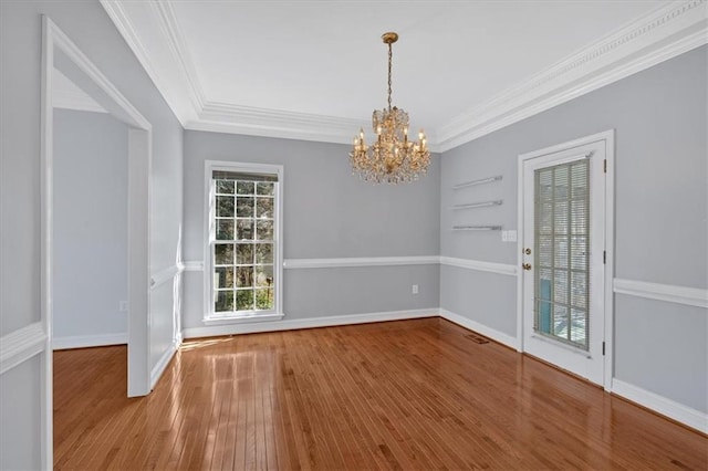 unfurnished dining area with baseboards, an inviting chandelier, crown molding, and hardwood / wood-style flooring