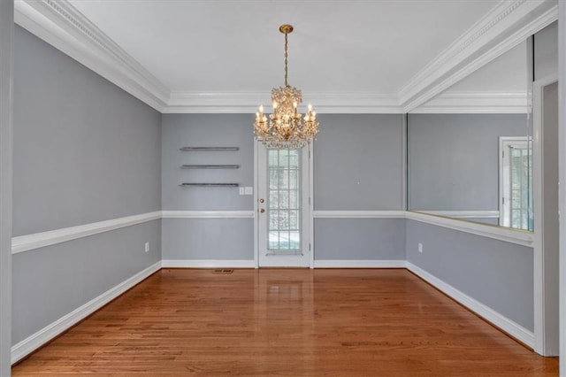 unfurnished dining area featuring baseboards, wood finished floors, a chandelier, and crown molding