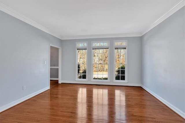 spare room with baseboards, wood finished floors, and ornamental molding