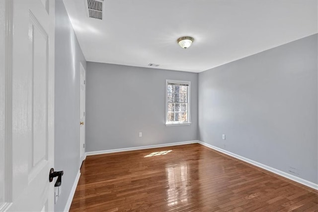 empty room with visible vents, baseboards, and hardwood / wood-style floors