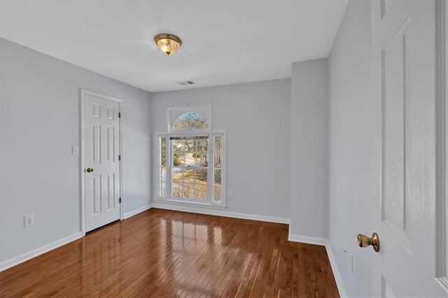 unfurnished room with visible vents, baseboards, and wood finished floors