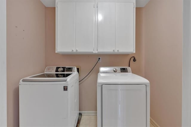 laundry room featuring washer and dryer, cabinet space, and baseboards