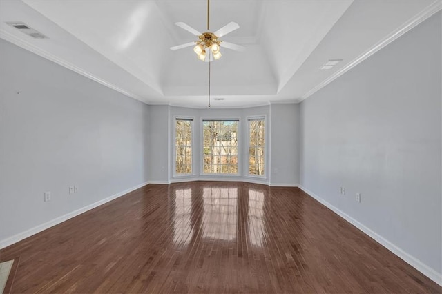 spare room featuring visible vents, a raised ceiling, baseboards, and wood finished floors