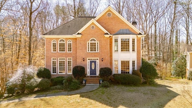 view of front facade with brick siding and a chimney