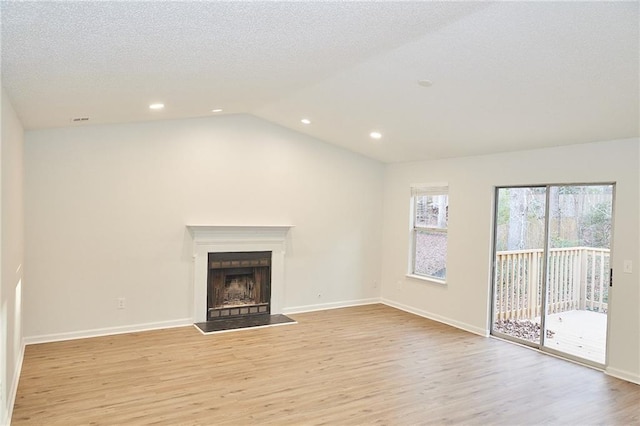 unfurnished living room with a textured ceiling, vaulted ceiling, and light wood-type flooring