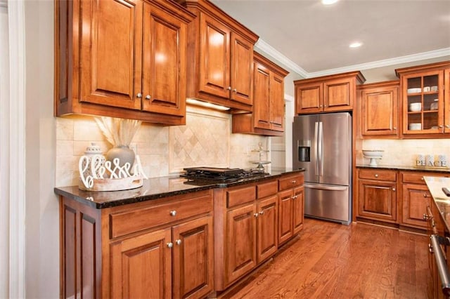 kitchen featuring stainless steel fridge with ice dispenser, backsplash, crown molding, hardwood / wood-style floors, and dark stone counters