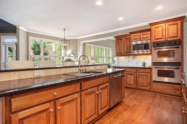 kitchen with sink, stainless steel appliances, a notable chandelier, light hardwood / wood-style floors, and ornamental molding