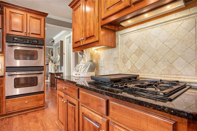 kitchen featuring black gas cooktop, ornamental molding, double oven, tasteful backsplash, and light hardwood / wood-style floors