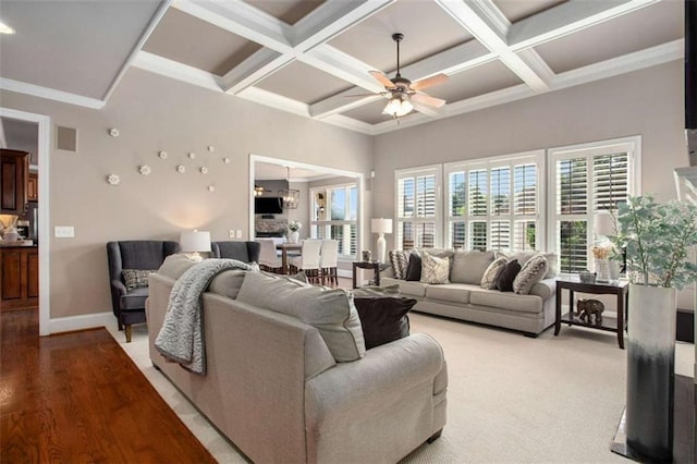 living room with ornamental molding, coffered ceiling, ceiling fan with notable chandelier, beamed ceiling, and hardwood / wood-style floors