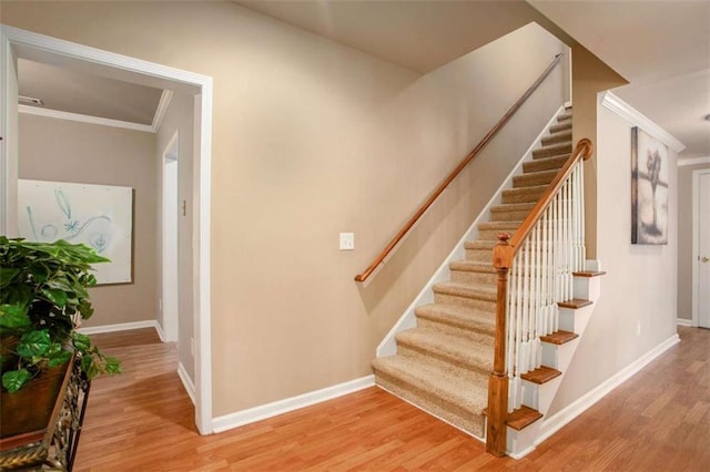 staircase with hardwood / wood-style floors and crown molding