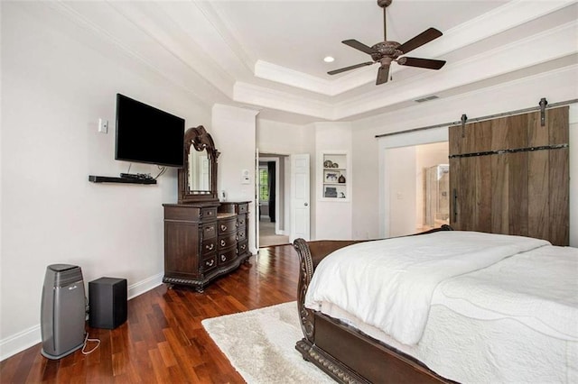 bedroom featuring ceiling fan, a barn door, dark hardwood / wood-style flooring, crown molding, and a tray ceiling