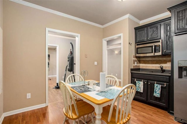 dining space with light hardwood / wood-style floors, ornamental molding, and sink