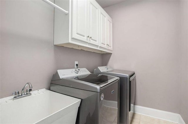 washroom with light tile patterned flooring, cabinets, sink, and washing machine and clothes dryer