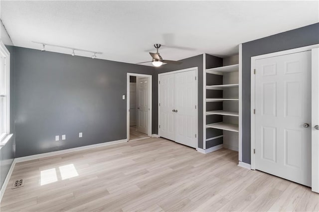 342 Spring Valley Rd, Waynesboro, GA 30830 - unfurnished bedroom with rail lighting, light wood-type flooring, baseboards, and two closets