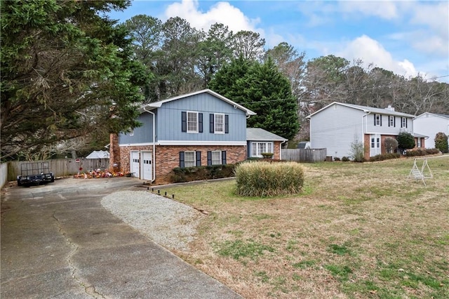 tri-level home featuring aphalt driveway, an attached garage, brick siding, and fence