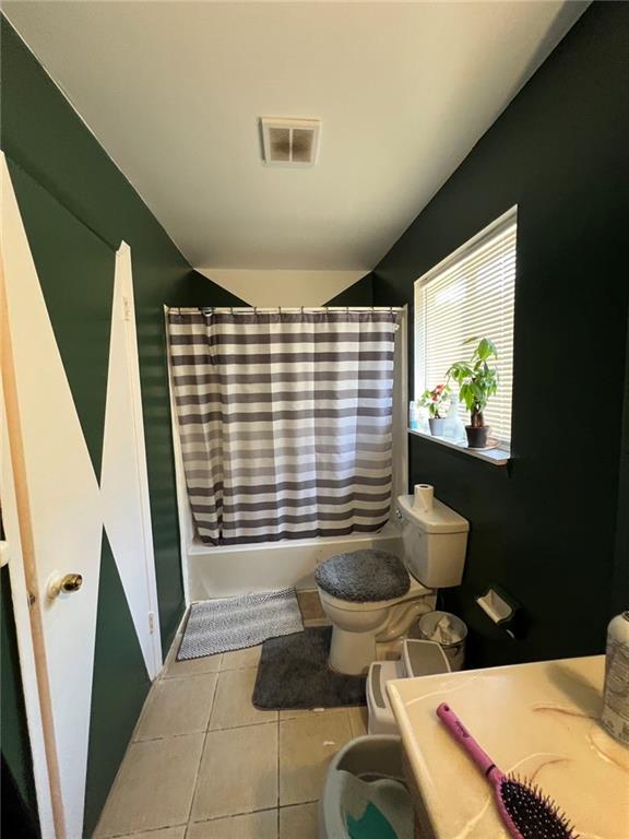 bathroom featuring toilet, shower / bathtub combination with curtain, and tile patterned flooring